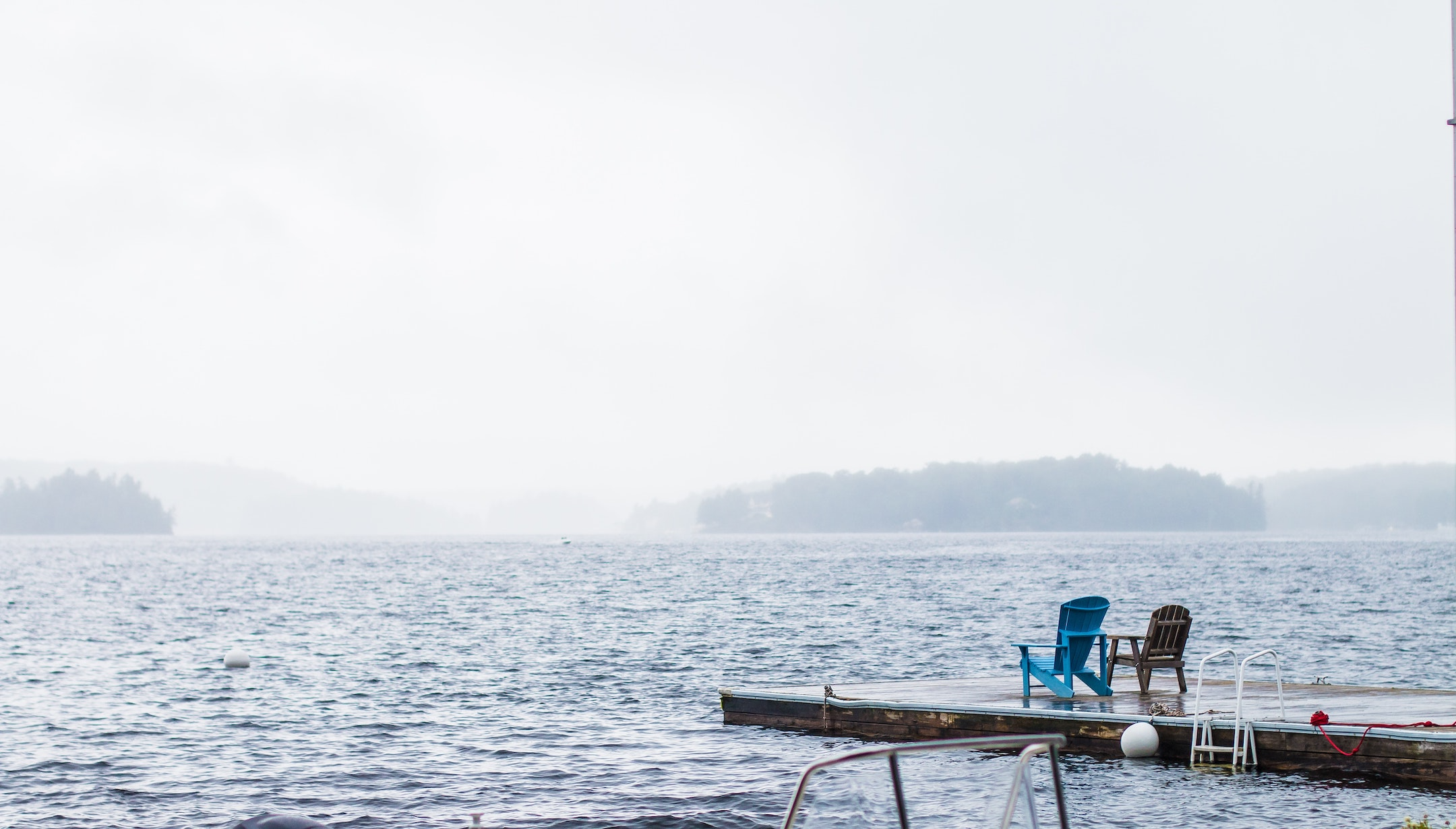 Muskoka chairs on dock by lake.